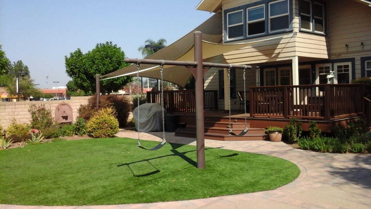 Real custom shade sail installation with red fabric over a residential patio